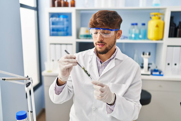 Young arab man scientist analysing plant test tube at laboratory - Photo, Image
