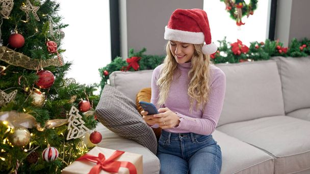 Молода блондинка святкує Різдво за допомогою смартфона вдома - Фото, зображення