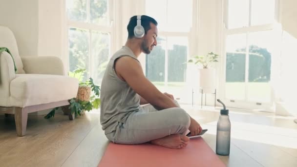Man, fitness en hoofdtelefoon voor thuis yoga, audio streaming en workout muziek met vrolijke energie op de vloer. Jongeren op mobiel, luisteren naar audio en geestelijke gezondheid of motivatie in pilates training. - Video