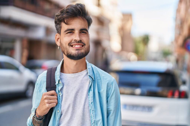 Молодий іспаномовний студент усміхається впевнено носити рюкзак на вулиці
 - Фото, зображення