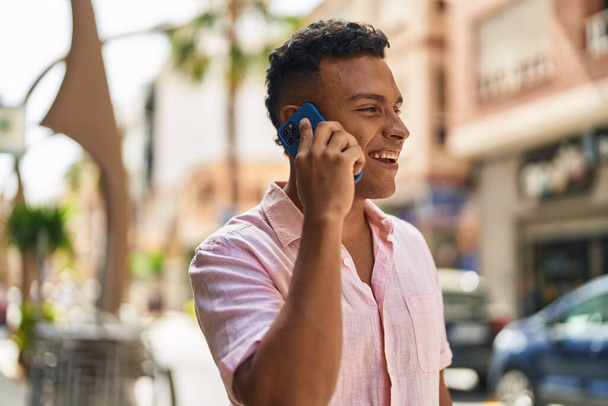 Молодий латинський чоловік посміхається впевнено говорити по смартфону на вулиці
 - Фото, зображення
