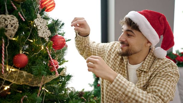 Young arab man decorating christmas tree at home - Photo, Image