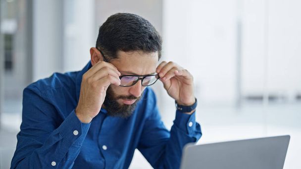 Giovane uomo d'affari ispanico che indossa gli occhiali utilizzando il computer portatile che lavora in ufficio - Foto, immagini