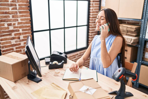 若い美しいパニック女性電子商取引労働者スマートフォンで話すノートブック上のオフィスで書く - 写真・画像