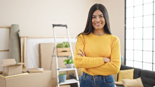 Young beautiful hispanic woman smiling confident standing with arms crossed gesture at new home - Foto, imagen
