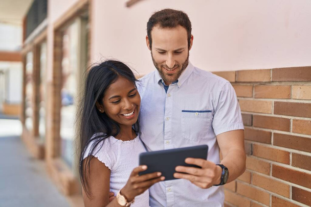 Man and woman interracial couple standing together using touchpad at street - Foto, Bild