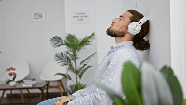 Jovem hispânico ouvindo música relaxada na cadeira na sala de espera - Foto, Imagem