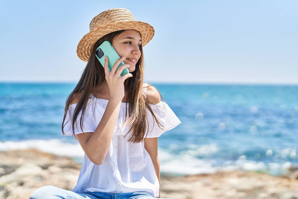 愛らしい女の子観光客笑顔自信を持って話して上のスマートフォンで海辺 - 写真・画像