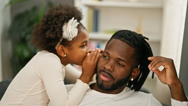 Afro-americano padre e figlia seduti sul divano raccontando segreti a casa - Foto, immagini