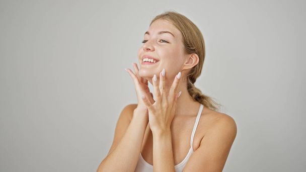 Giovane donna bionda sorridente fiducioso massaggio viso su sfondo bianco isolato - Foto, immagini