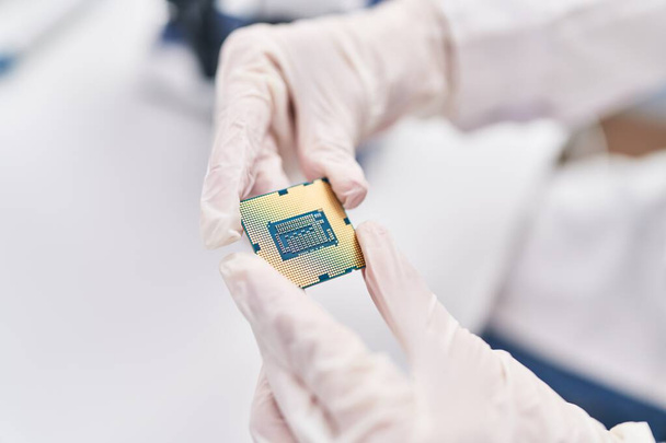 Young blonde woman scientist holding cpu processor chip at laboratory - Photo, Image