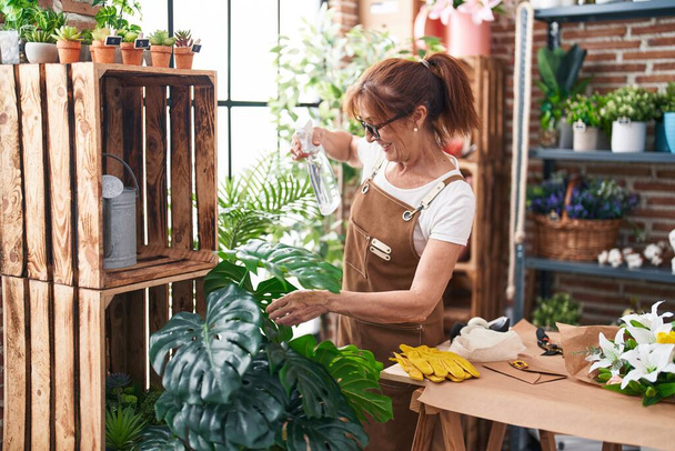 Средневековая флористка, использующая дифюзер, работающая в цветочном магазине. - Фото, изображение