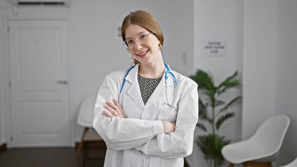 Young blonde woman doctor smiling confident standing with arms crossed gesture at clinic waiting room - Photo, Image