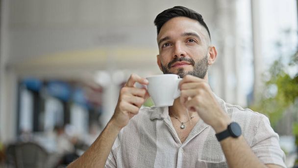 コーヒーショップテラスでコーヒーを飲む若いヒスパニック男性 - 写真・画像