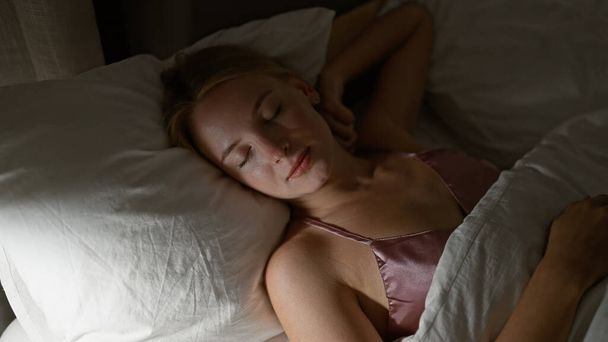 Mujer rubia joven acostada en la cama durmiendo en el dormitorio - Foto, imagen