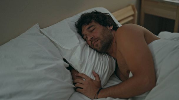 若いですヒスパニック男寝そべってベッドの上に寝そべっている - 写真・画像