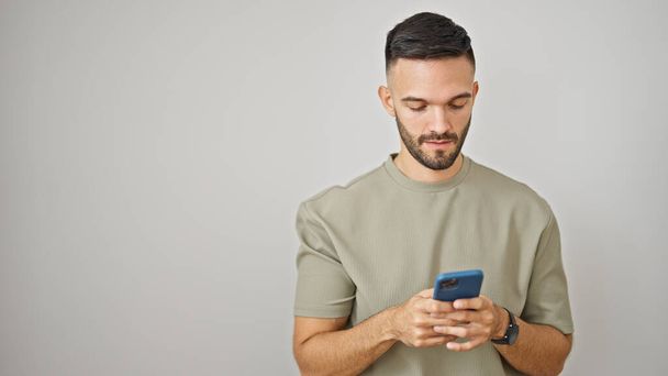 Young hispanic man using smartphone over isolated white background - Fotoğraf, Görsel