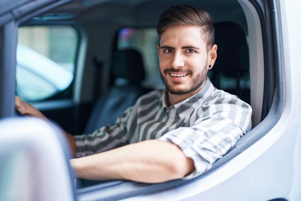Νεαρός καυκάσιος άνδρας χαμογελά αυτοπεποίθηση οδήγηση αυτοκινήτου στο δρόμο - Φωτογραφία, εικόνα