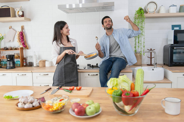 Heureux jeune couple cuisiner ensemble dans le comptoir de la cuisine à la maison - Photo, image
