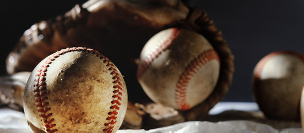 старые винтажные бейсбольные перчатки и мячи на темном фоне  - Фото, изображение