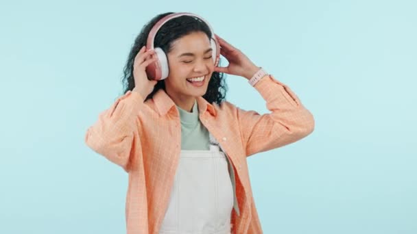 Happy woman, dance or music headphones in studio for celebration of freedom, party or hearing audio song on blue background. Excited model listening to multimedia podcast, sound or radio subscription. - Footage, Video