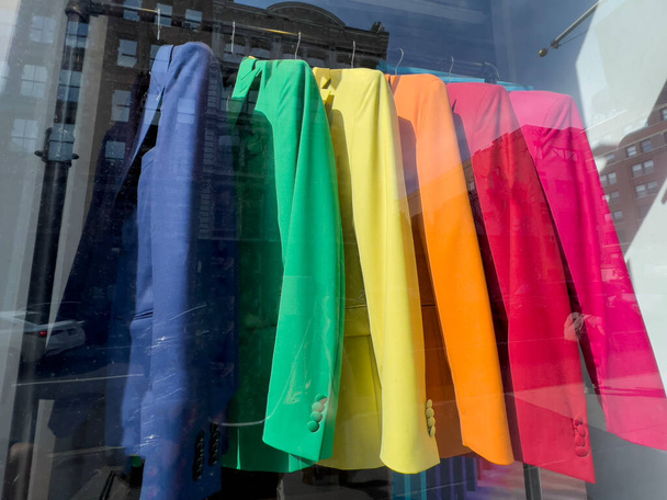 lgbt trots, kleurrijke kleding en jassen op hangers in etalage weergave van een winkel of boetiek voor lgbt trots dag. winkelconcept. etalage met kleurrijke kleding - Foto, afbeelding