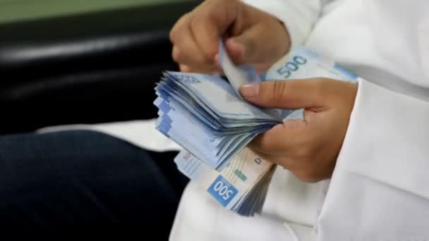 benadering van de handen van een vrouw in een witte jas tellen Mexicaanse bankbiljetten - Video