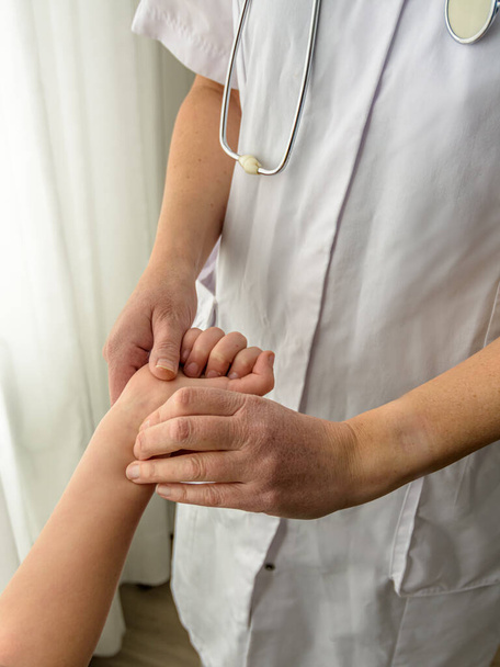 Um pediatra verifica o ritmo cardíaco de uma criança no pulso - Foto, Imagem