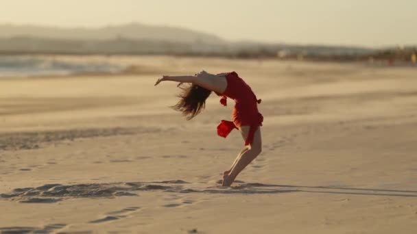 Изящная эмоциональная женщина в красном платье, танцующая на песке. Средний выстрел - Кадры, видео