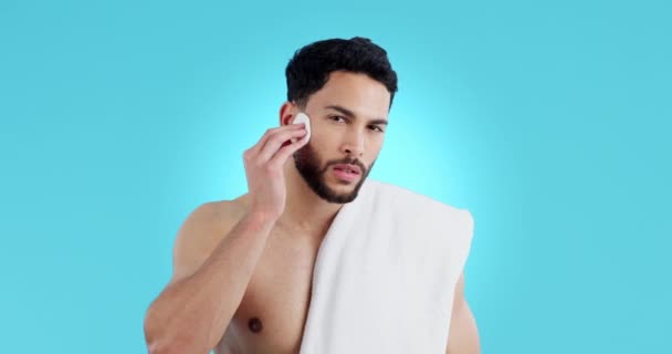 Face, skincare and man with cotton in studio for dermatology, cosmetics or wellness on blue background. Portrait, cleaning and male model with beauty pad for swab application, toner or facial cleanse. - Footage, Video