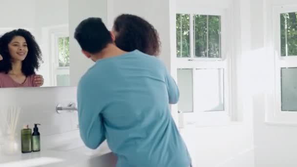 Love, hygiene and couple brushing teeth in the bathroom together on a weekend morning routine. Happy, hug and young man and woman doing treatment for dental health or oral care at modern apartment - Footage, Video