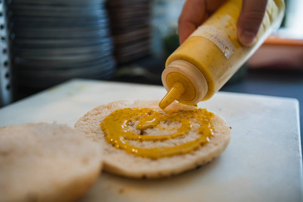 Cuire en ajoutant de la sauce moutarde au pain de bagel pour la préparation d'un brunch dans un café. - Photo, image
