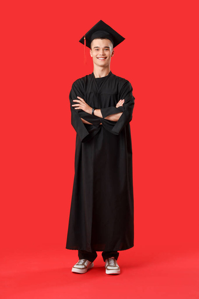 Male graduate student on red background - Foto, Imagen