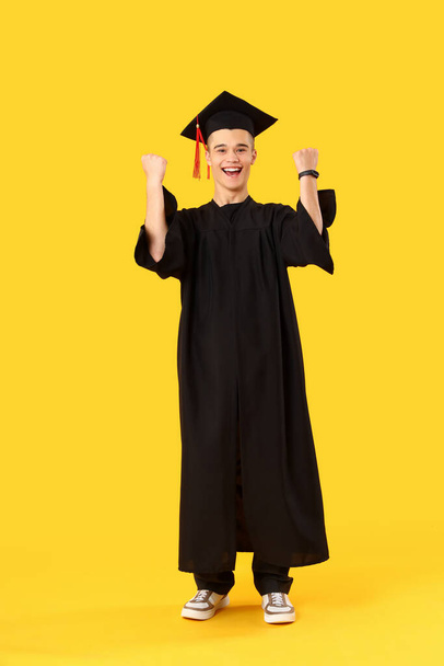 Happy male graduate student on yellow background - Zdjęcie, obraz