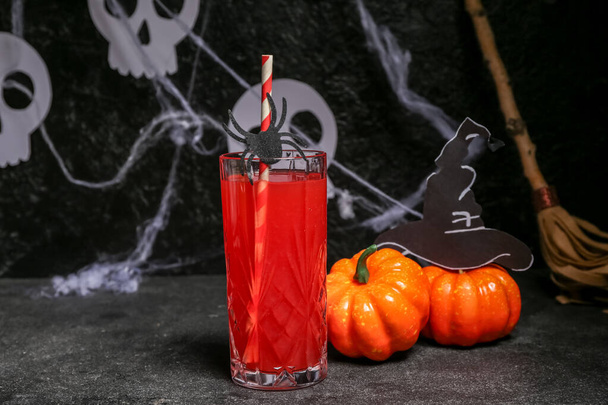 Verre de délicieux cocktail rouge pour Halloween et citrouilles sur fond sombre - Photo, image
