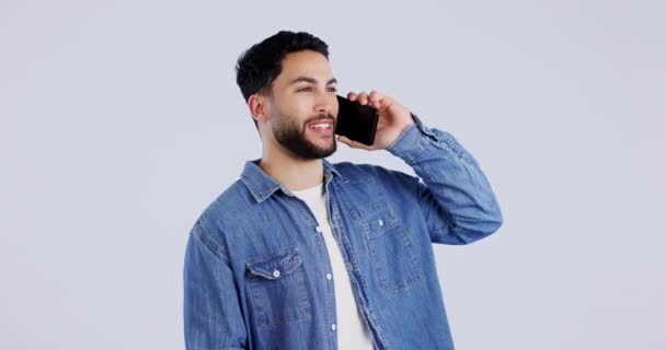 Man, talking and phone call in studio for contact, networking or funny conversation on white background. Happy indian model, mobile communication and laugh on smartphone for chat, discussion or hello. - Footage, Video