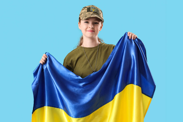Joven soldado con bandera de Ucrania sobre fondo azul claro - Foto, Imagen