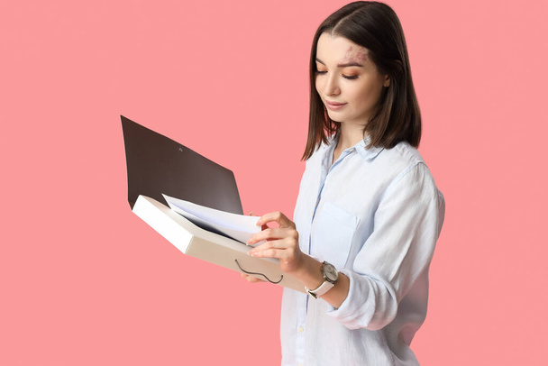 Młoda bizneswoman z folderem na różowym tle - Zdjęcie, obraz