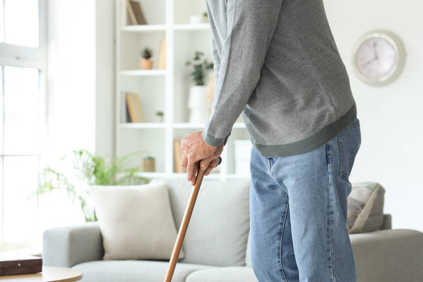 Senior man loopt met stok thuis, close-up - Foto, afbeelding