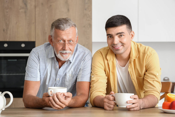 Älterer Mann mit Sohn trinkt Tee in Küche - Foto, Bild
