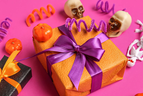 Κουτιά δώρων, κολοκύθες και κρανία για τον εορτασμό του Halloween σε ροζ φόντο, κοντινό πλάνο - Φωτογραφία, εικόνα