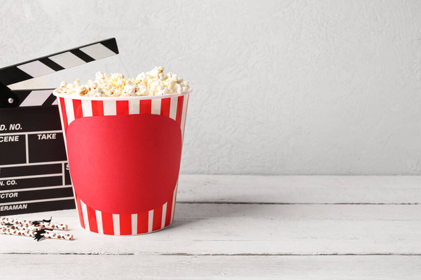 Popcorn kbelík s film clapperboard a halloween brčka na dřevěném stole proti bílému pozadí - Fotografie, Obrázek