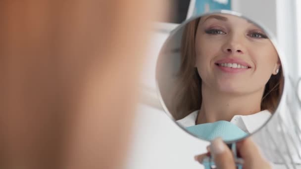 W lustrze widać wyraźną poprawę stanu zębów po wizycie u dentysty. Kobieta cieszy się, że może się uśmiechać bez kompleksów z powodu jej cudownego uśmiechu. - Materiał filmowy, wideo