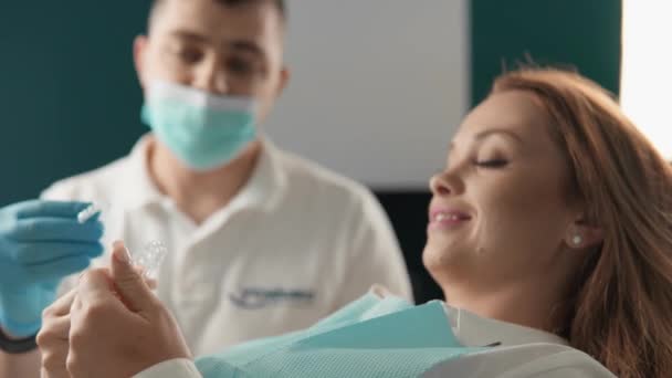 De tandarts legt de patiënt de principes van het gebruik van uitlijnaars om de beet te corrigeren. De patiënt krijgt professioneel advies in een tandheelkundige kliniek over het gebruik van uitlijnaars. Hoge kwaliteit 4k beeldmateriaal - Video