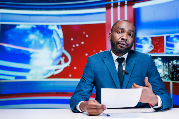 Presenter delivering news from papers headlines, reporting exclusive information about latest events worldwide. African american news anchor transmitting details about business or politics. - Photo, Image