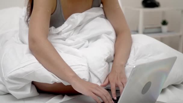 Dizüstü bilgisayarına odaklanmış bir kadın elleri, evdeki yatağının rahatlığından çevrimiçi sosyal ağlarda iletişim kuruyor..  - Video, Çekim