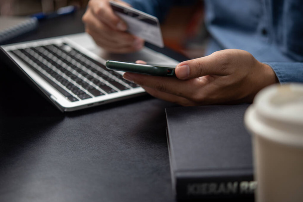 рука людини тримає кредитну картку і використовує смартфон для онлайн-покупки. - Фото, зображення