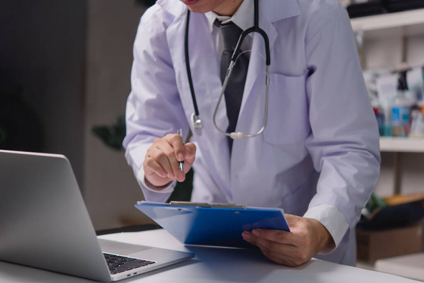 muž lékař ruka drží pero pracovní informace o pacientovi v kontrolním papíru na schránce. Koncepce zdravotní péče a pojištění. - Fotografie, Obrázek