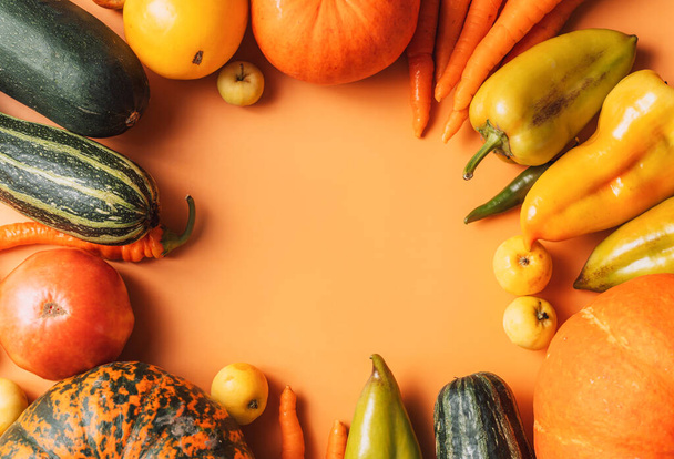 Récolte automnale de légumes mûrs sur fond orange avec un espace vide au centre. - Photo, image