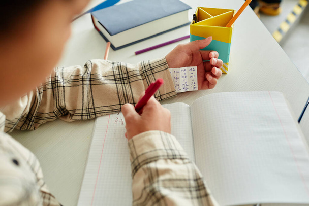 Κοντινό πλάνο του αγνώριστο νεαρό αγόρι εξαπάτηση κατά τη διάρκεια του τεστ στο σχολείο και κρύβοντας σημείωμα στο μανίκι, αντιγραφή χώρου - Φωτογραφία, εικόνα